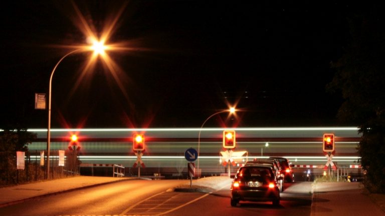 Lichtstreifen eines Zuges am Bahnübergang bei Nacht
