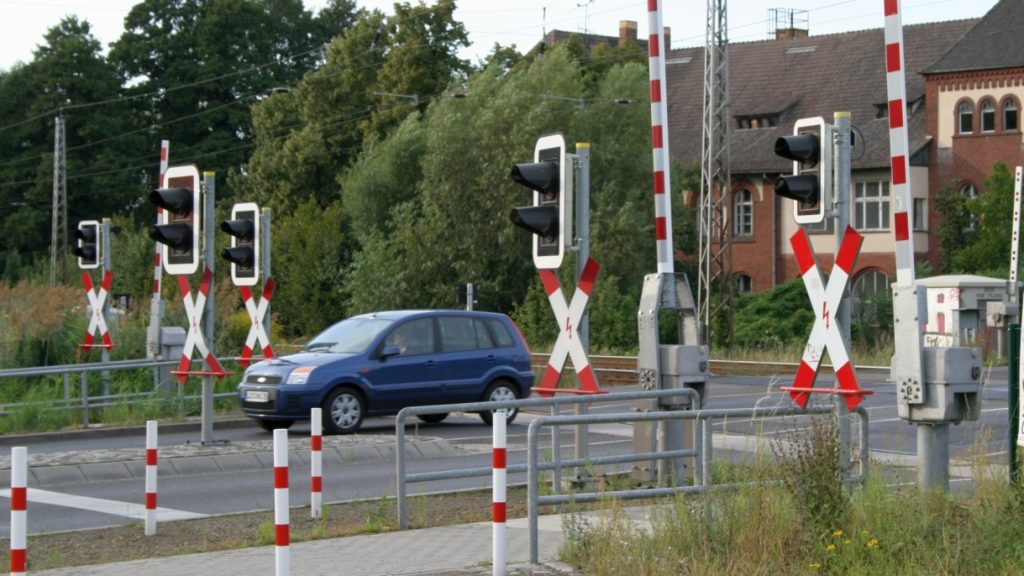 Pkw fährt über Bahnübergang mit vielen Andreaskreuzen und Lichtzeichen